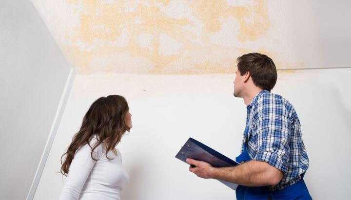 A homeowner and professional assess the damage of a ceiling during expert water damage restoration in a home in Modesto, CA.